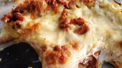 a cheesy croissant breakfast bake by Cleveland cooking served to guests. the bake includes bacon, egg, croissants, onion, and cheese.