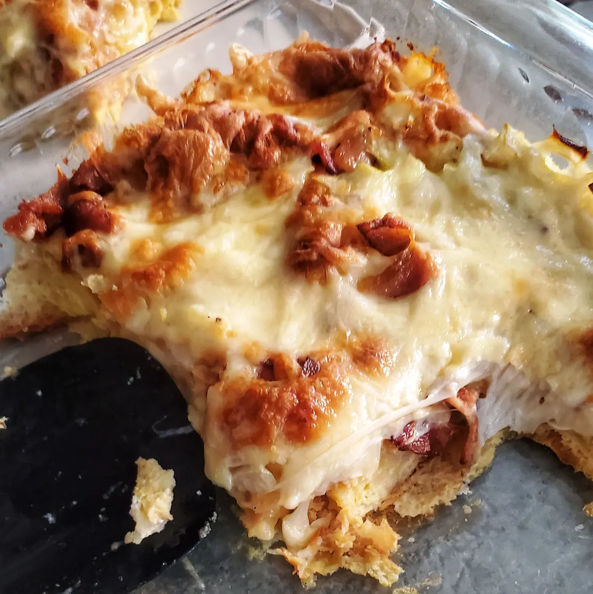 a cheesy croissant breakfast bake by Cleveland cooking served to guests. the bake includes bacon, egg, croissants, onion, and cheese.