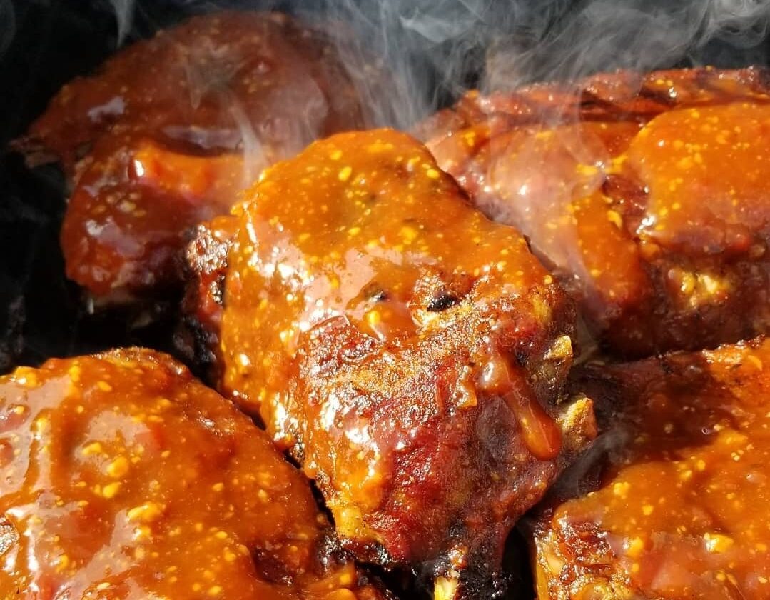 Memphis barbecue sauce on ribs that are being cooked on a grill