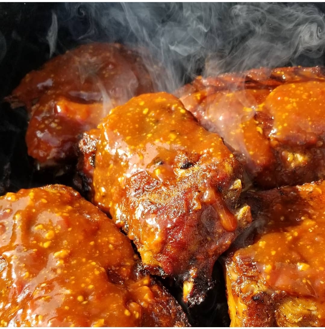 Memphis barbecue sauce on ribs that are being cooked on a grill