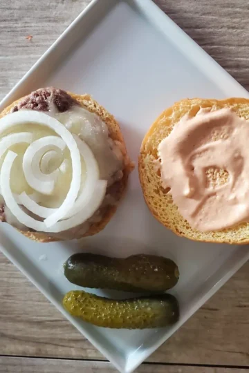 two ingredient Turkey Burger recipe from cleveland cooking. The burger has my everything sauce and onions on it with two pickles on the side.