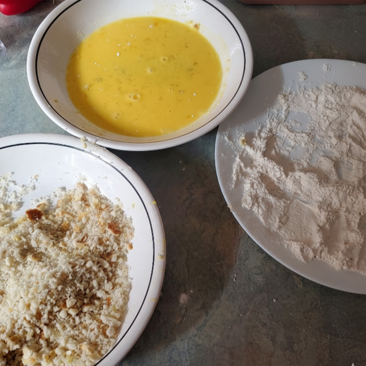 breading station for city Chicken recipe. a bowl of whipped eggs, a bowl of breadcrumbs and a bowl of flour