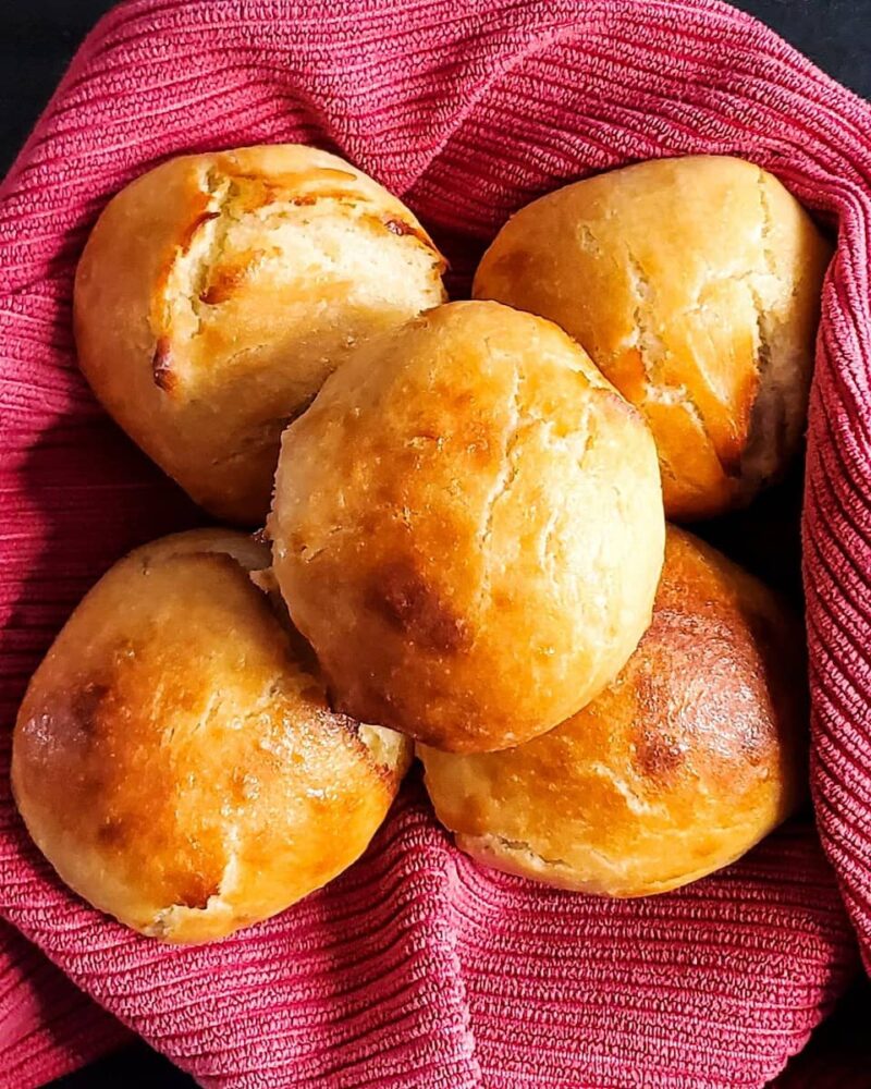 Easy buns recipe from Cleveland Cooking. Easy buns in a basket lined with a red cloth. The buns have a glaze of butter and sugar.