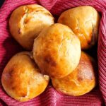 Easy buns recipe from Cleveland Cooking. Easy buns in a basket lined with a red cloth. The buns have a glaze of butter and sugar.