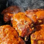 Memphis barbecue sauce on ribs that are being cooked on a grill