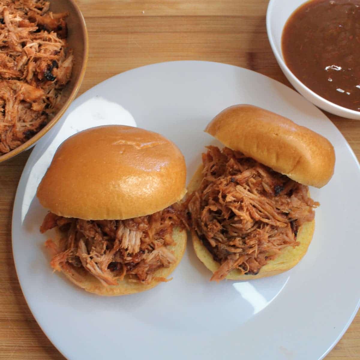 barbecue pulled pork sandwiches with bowls of pulled pork and barbecue sauce near. The pulled pork recipe is from cleveland cooking.