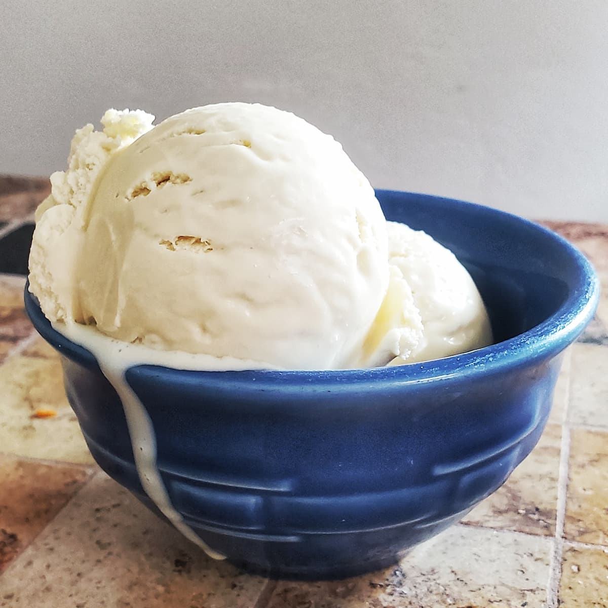 homemade vanilla ice cream from Cleveland cooking. 2 scoops of homemade vanilla ice cream in a blue bowl.