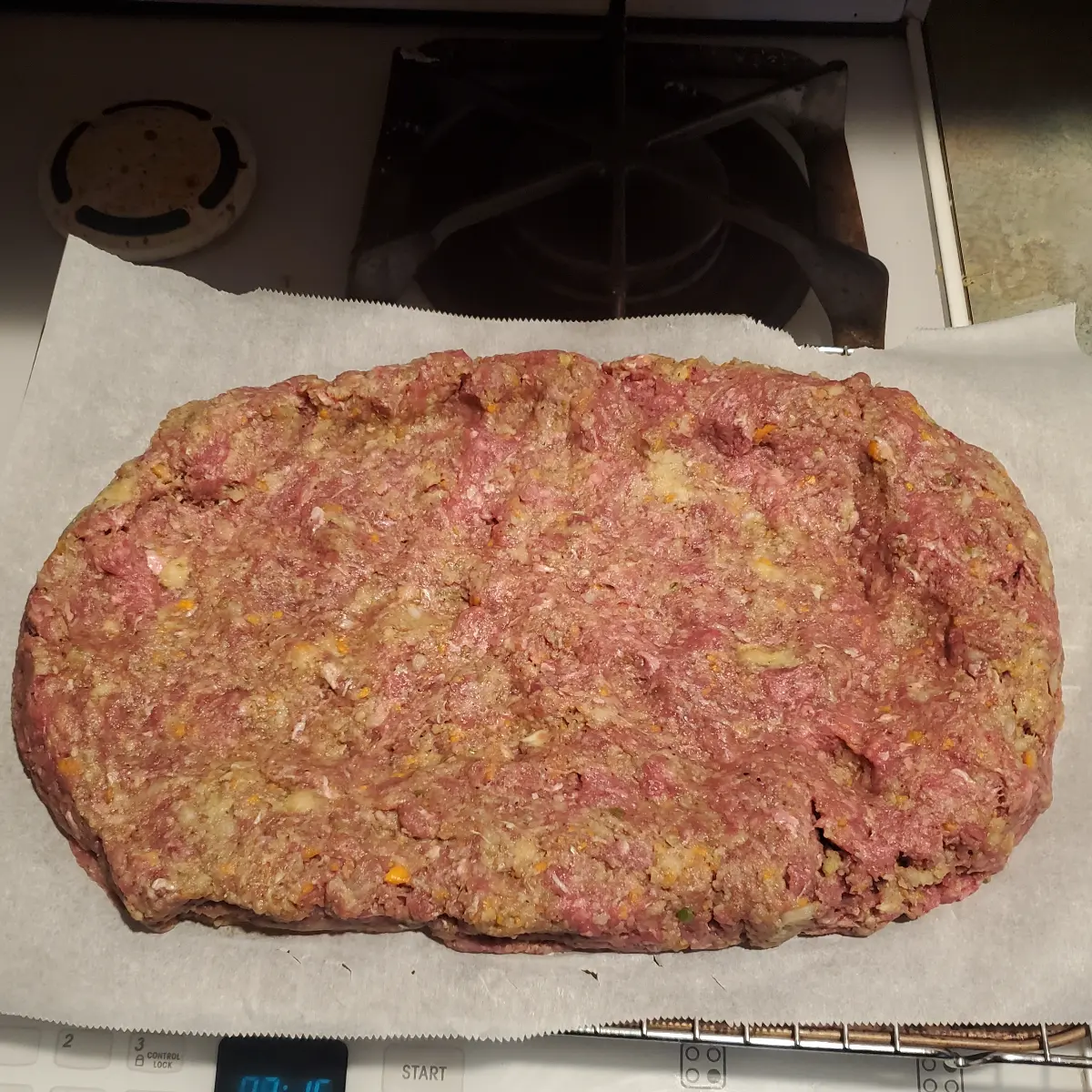 a formed meatloaf on top of my stove. The meatloaf recipe is from Clevelandcooking.com. The sides of the formed meatloaf are turned up to make sure the topping stays on. the meatloaf is about 2 inches high and 13 inches long, 9 inches wide.