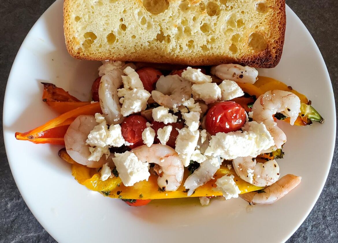 roasted peppers, garlic, and cherry tomatoes with shrimp, feta, and a basil dressing. A side of toasted bread on the side