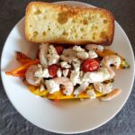 roasted peppers, garlic, and cherry tomatoes with shrimp, feta, and a basil dressing. A side of toasted bread on the side