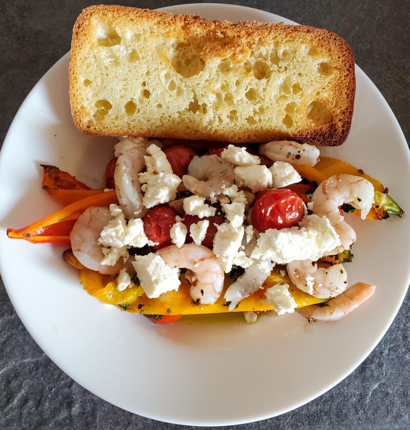 roasted peppers, garlic, and cherry tomatoes with shrimp, feta, and a basil dressing. A side of toasted bread on the side