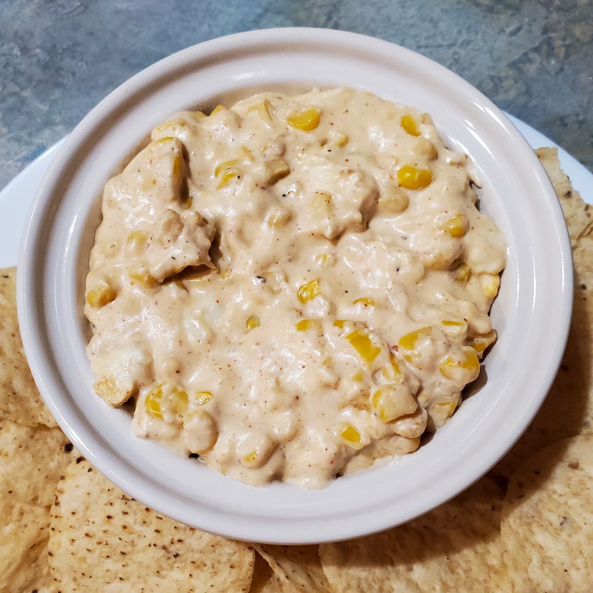 Street corn dip with corn, sour cream, mayonnaise, and spices. Served in a small bowl with tortilla chips. Party food recipe and an appetizer recipe.