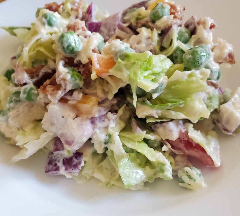 Make ahead layered salad from cleveland cooking. Lettuce, mayo, sugar, parmesan cheese, peas, bacon, onions, and bell peppers.