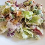 Make ahead layered salad from cleveland cooking. Lettuce, mayo, sugar, parmesan cheese, peas, bacon, onions, and bell peppers.