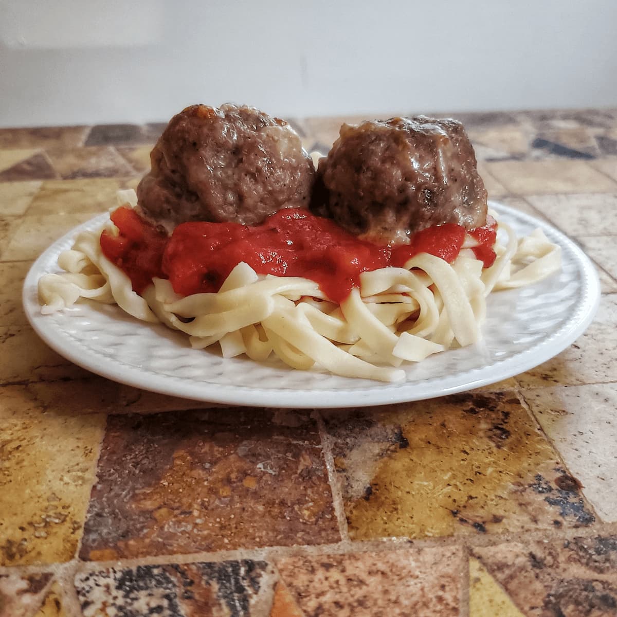 Cheesy meatballs on top of red sauce and pasta. Recipe from cleveland cooking