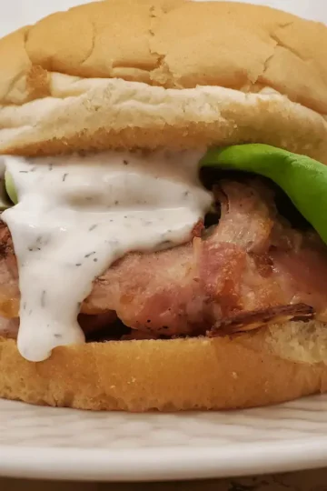 low carb bacon chicken cakes by Cleveland cooking. a low carb bacon chicken cakes on a bun with lettuce and ranch dressing.