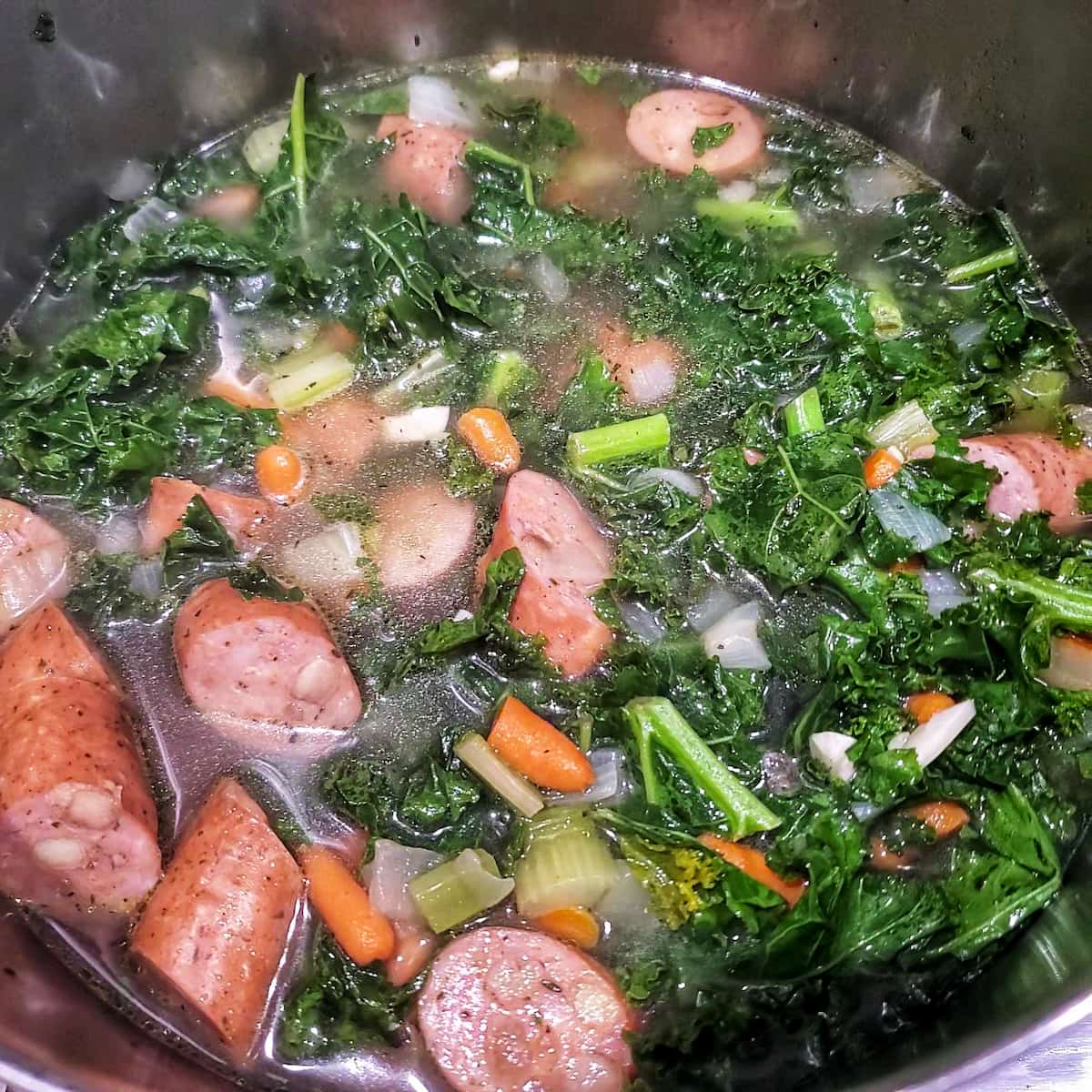 sausage and kale soup cooking on the stove by cleveland cooking