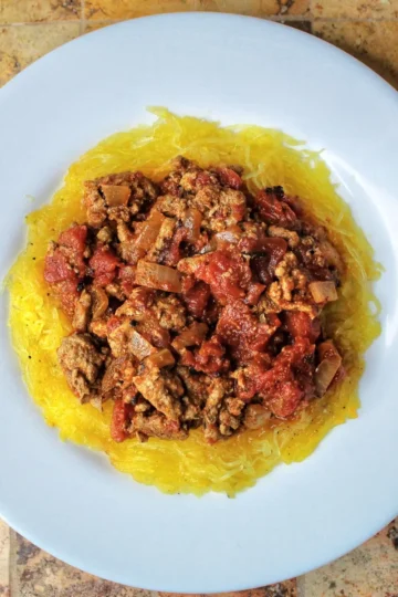 low carb Turkey chili with turkey, tomatoes, spices, and onions. The chili is on top of a bed of cooked spaghetti squash. recipe from cleveland cooking