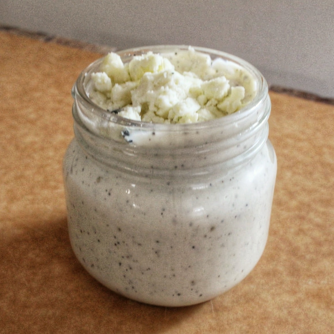 Blue cheese dressing recipe by Cleveland cooking. A mason jar filled with blue cheese dressing with pieces of blue cheese on top.