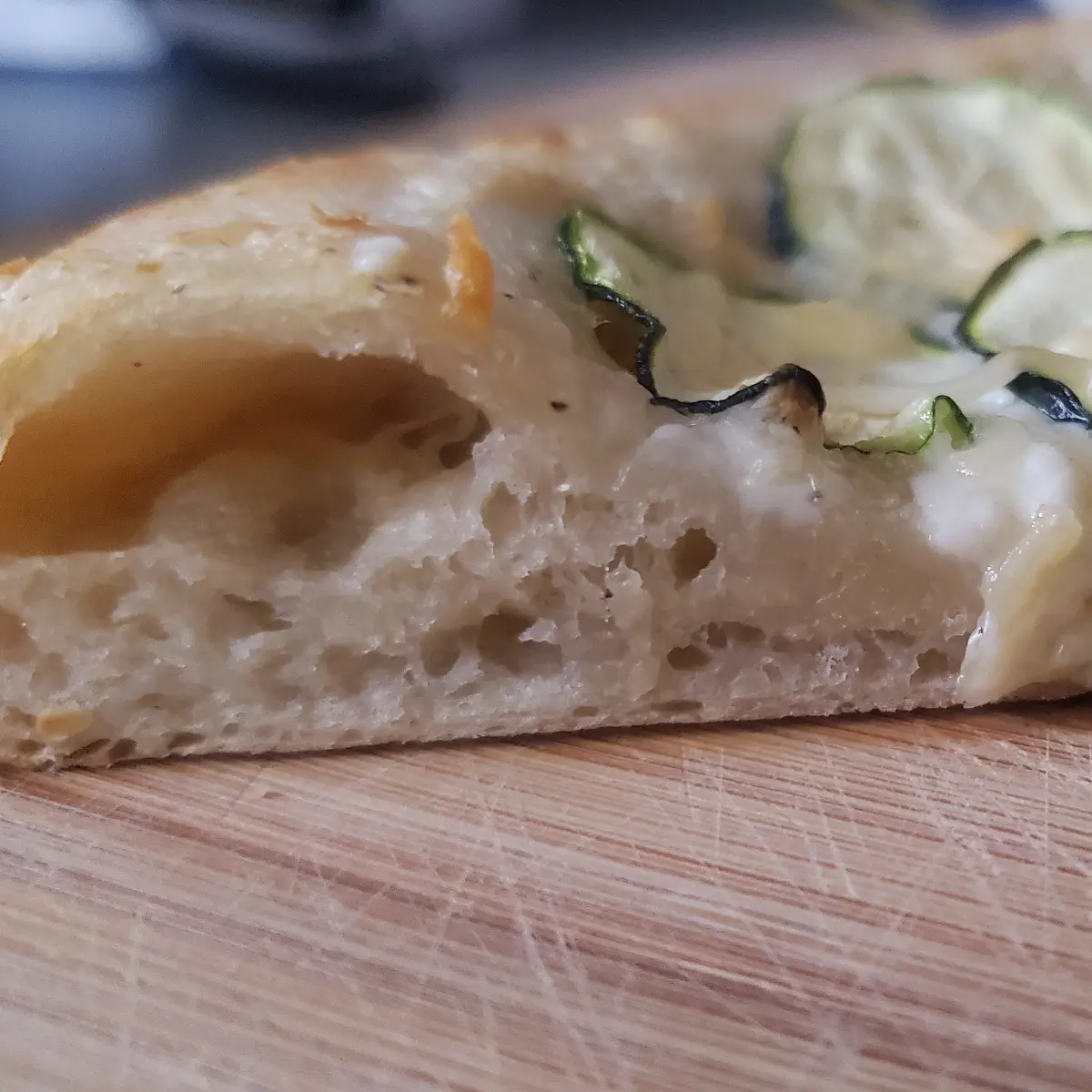 zucchini pizza from Cleveland cooking. a side view of the zucchini pizza by Cleveland cooking. The garlic cream sauce on a airy pizza dough with zucchini slices.