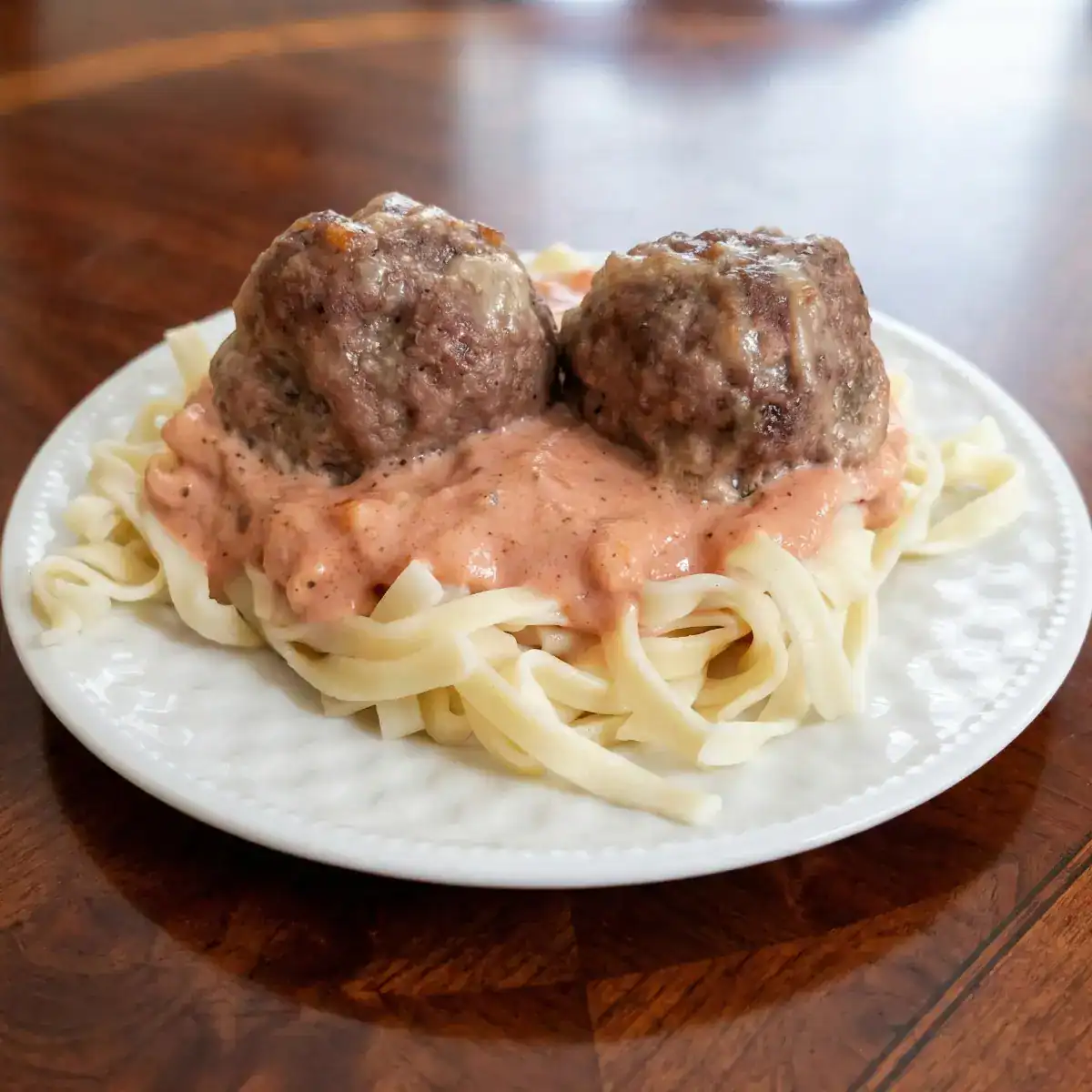 blush sauce recipe Cleveland cooking. 2 meatballs setting on top of a plate of homemade pasta with blush sauce.