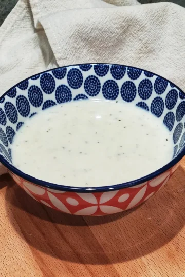 Creamy homemade Asiago cheese sauce served in a small colorful ceramic bowl.. Cleveland cooking