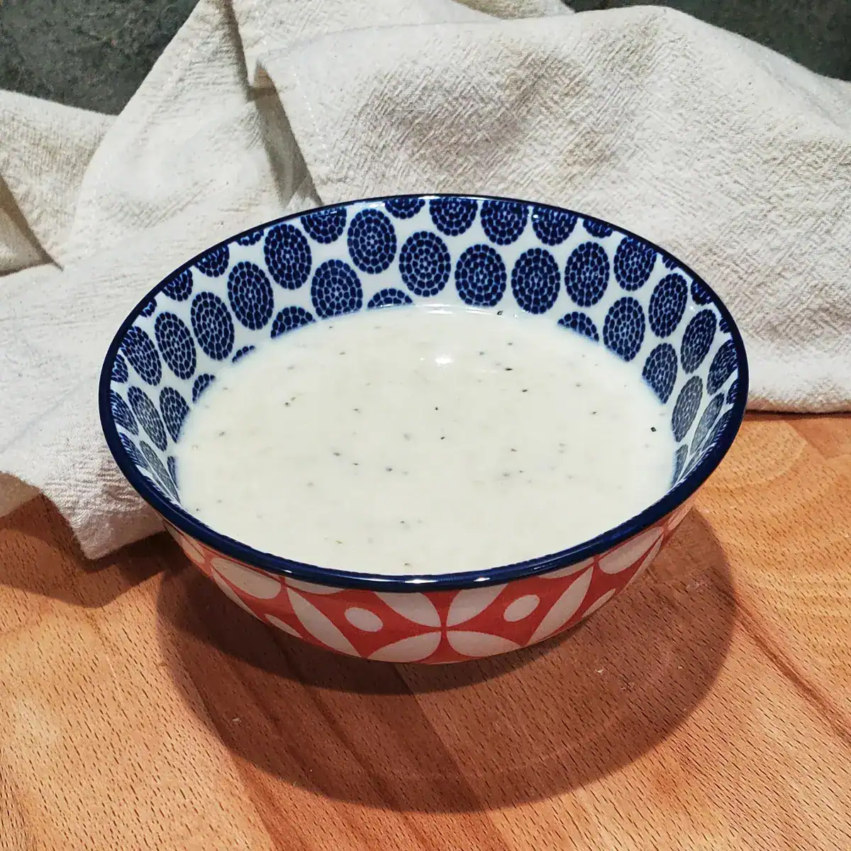 Creamy homemade Asiago cheese sauce served in a small colorful ceramic bowl.. Cleveland cooking