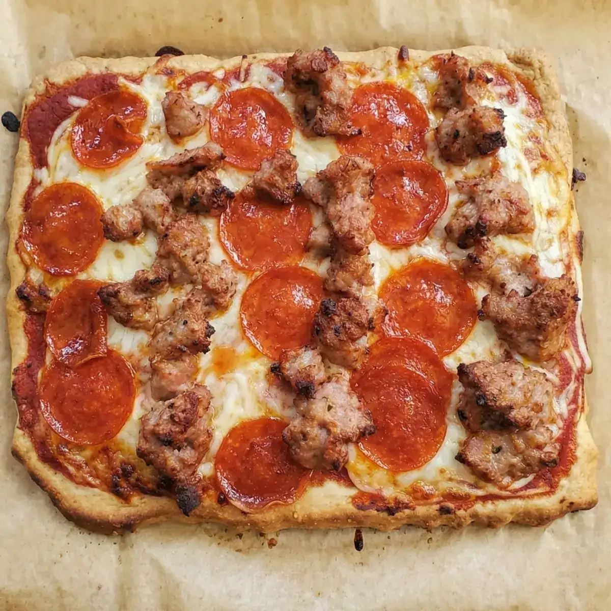 almond flour pizza crust. pizza with sausage and pepperoni toppings on a white plate. Cleveland cooking