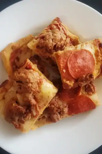 almond flour pizza crust. pizza with sausage and pepperoni toppings on a white plate. Cleveland cooking