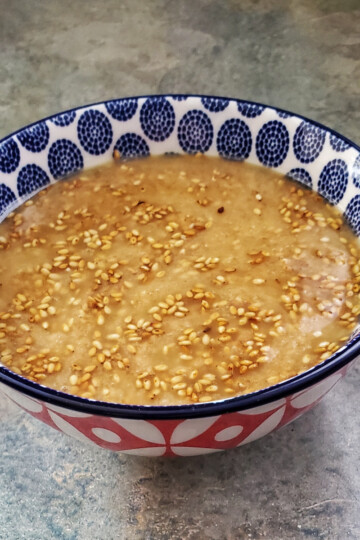 sesame ginger dressing in a colorful bowl with toasted sesame seeds floating in it. Cleveland cooking.