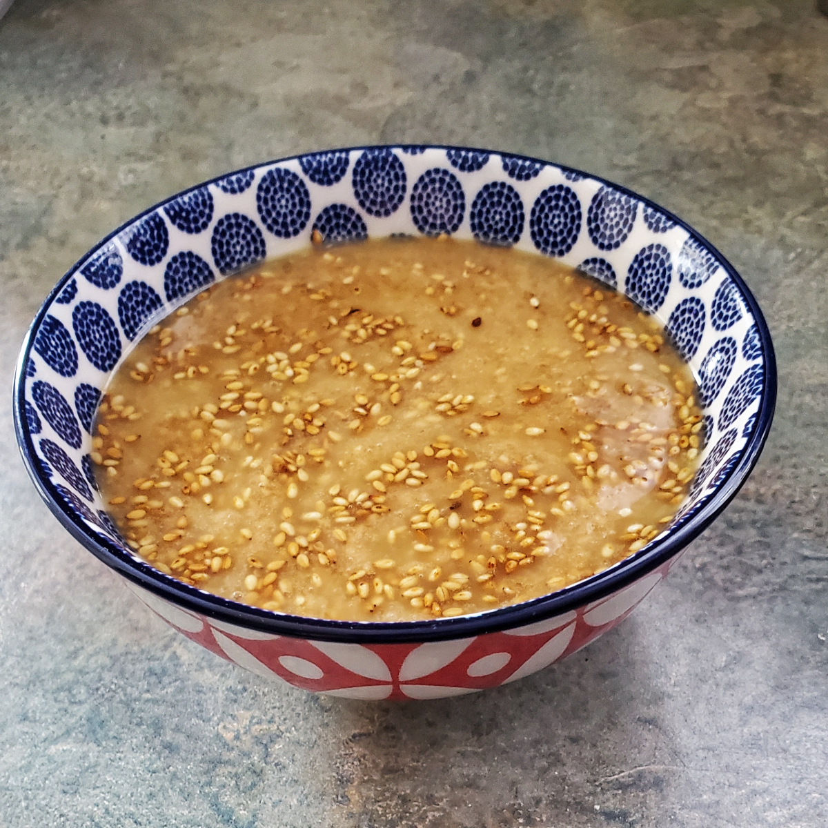 sesame ginger dressing in a colorful bowl with toasted sesame seeds floating in it. Cleveland cooking.