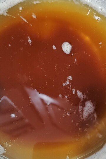 brown butter cooling in a bowl. There is a little bit of white milk solids around the edges.