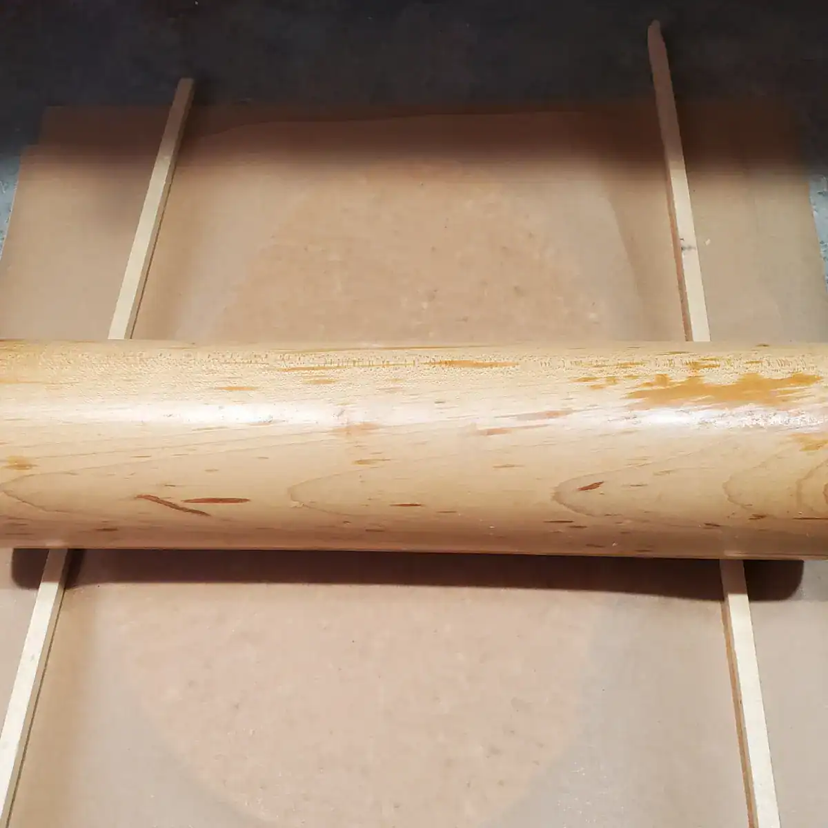 dough being rolled out by using ¼ inch dowels as a guide.