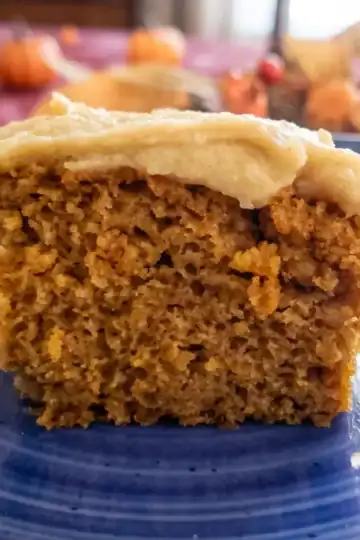 brown butter cream cheese frosting on top of a piece of pumpkin cake.